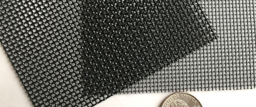 A coin besides two pieces of 316L stainless steel security screen for contrast. One piece is black, and the other piece is gray.